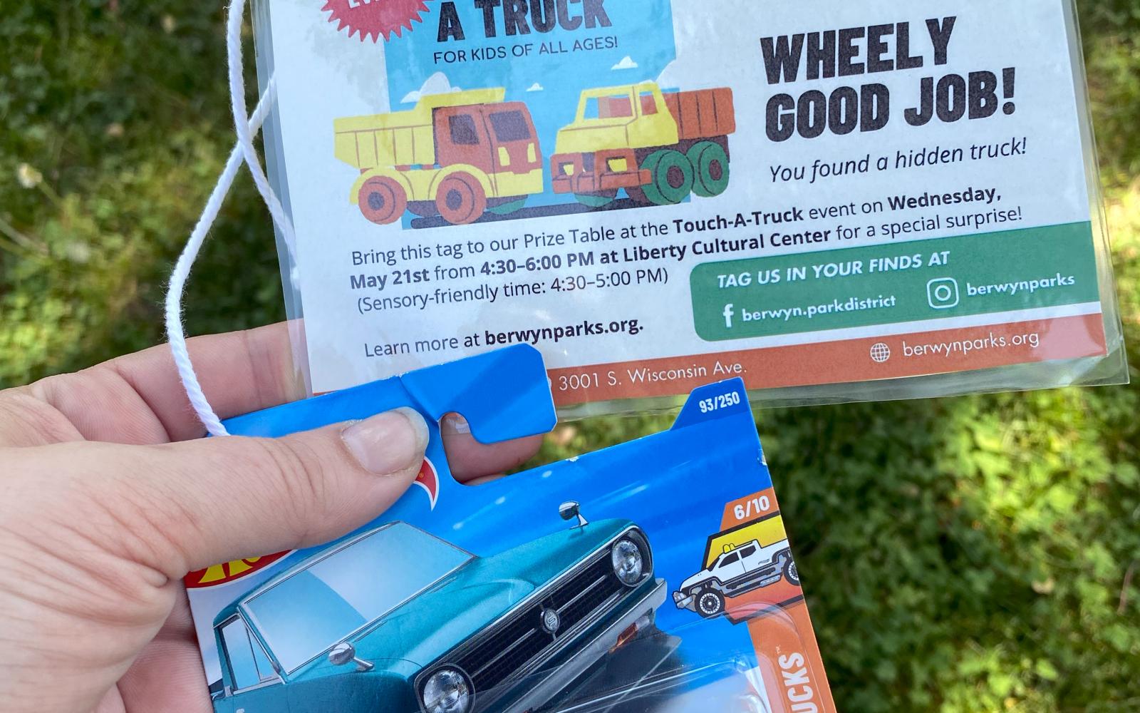 an image of a hot wheels truck in someone's hand with a background of grass for the touch-a-truck scavenger hunt