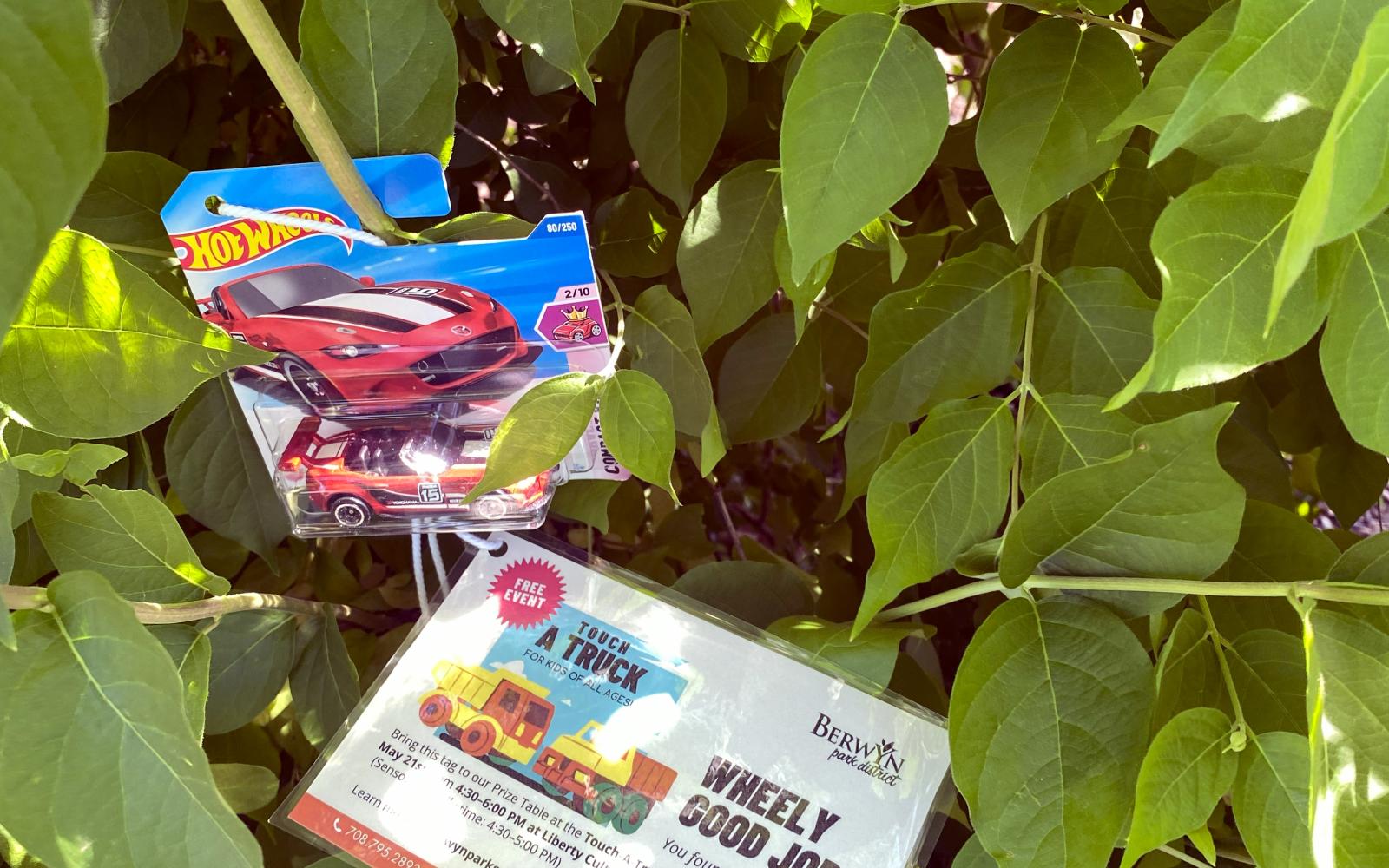 an image of a hot wheels truck hanging in a bush for the touch-a-truck scavenger hunt