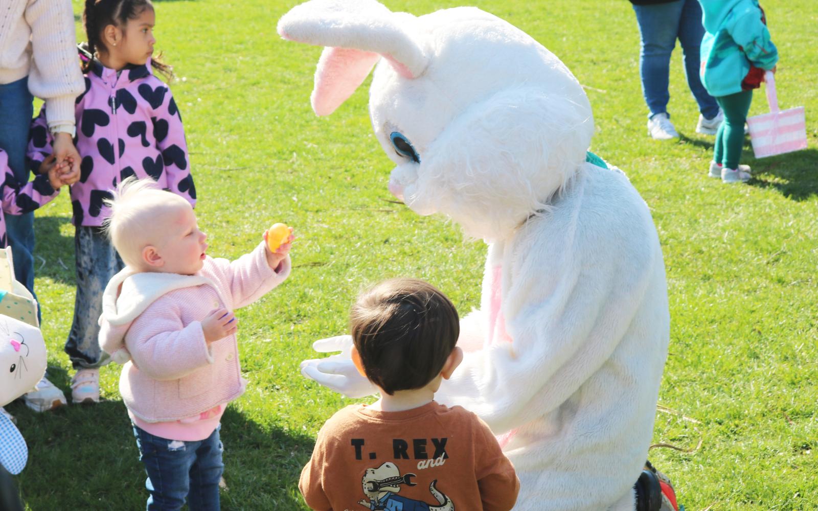 An image of a toddler holding out an Easter Egg for the bunny