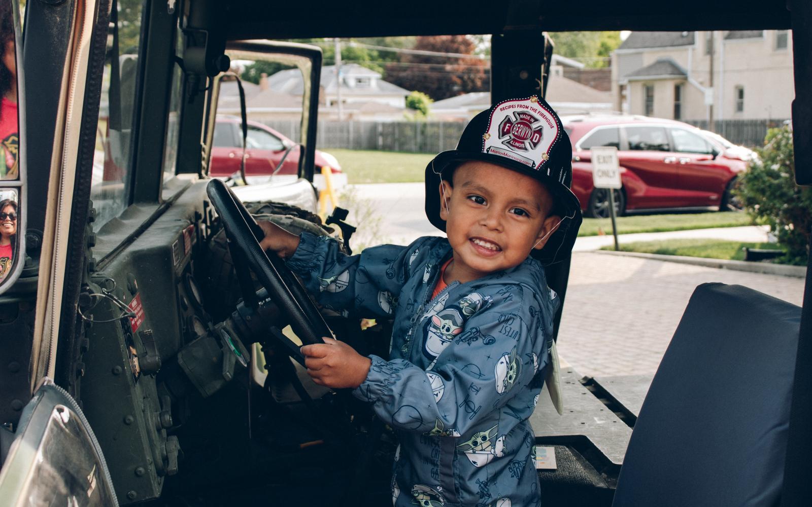 little kid in a firefighter hat at touch-a-truck