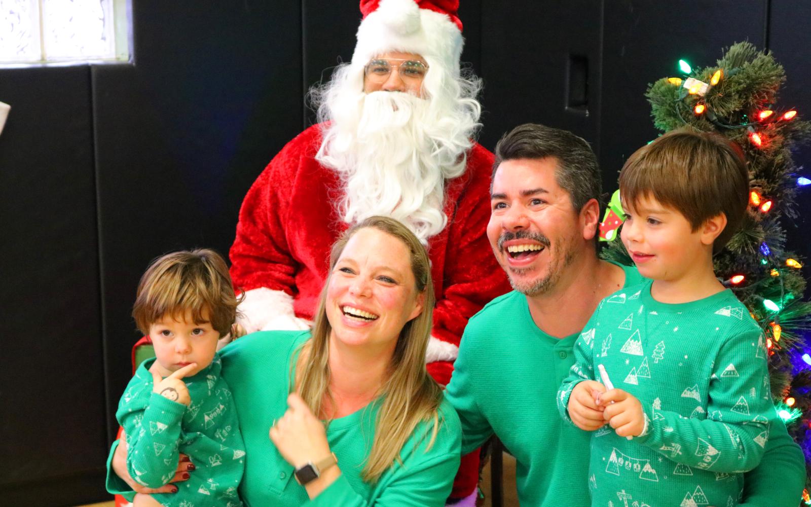 A photo of a family dressed in pajamas and posed around Santa Clause