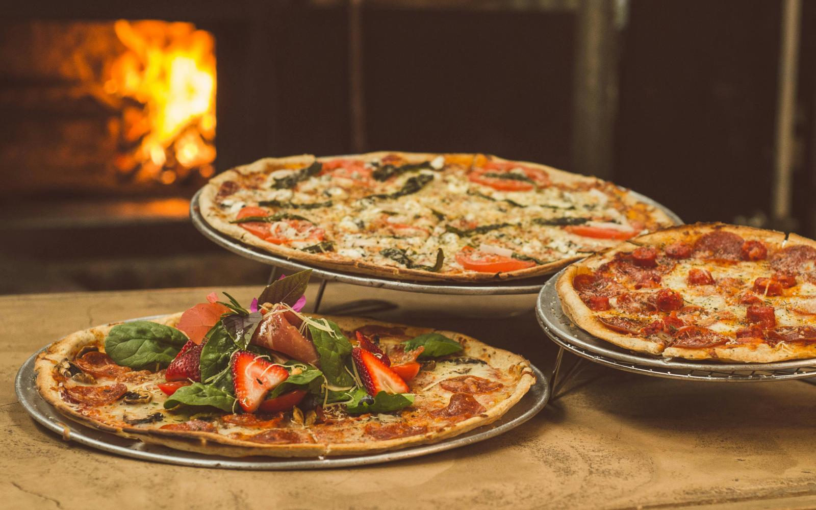 an image of three pizzas outside of a pizza oven