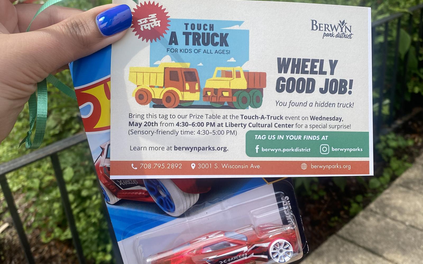 An image of a hand with a blue fingernail holding a hot wheels car and a tag that states that they found a hidden truck Bring this tag to our Prize Table at the Touch-A-Truck event on Wednesday, May 20th from 4:30–6:00 PM at Liberty Cultural Center for a special surprise! (Sensory-friendly time: 4:30–5:00 PM)