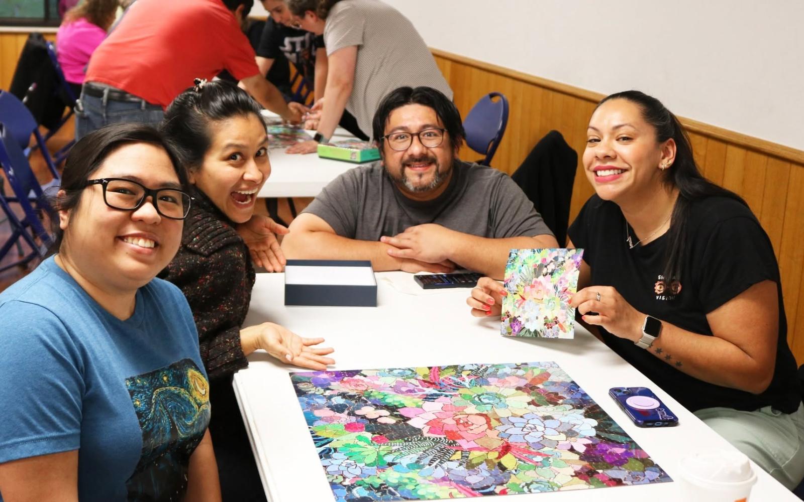 four people around a table with a finished puzzle