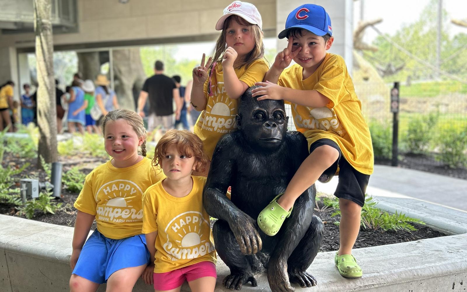 happy campers at the zoo, posing around a gorilla statue