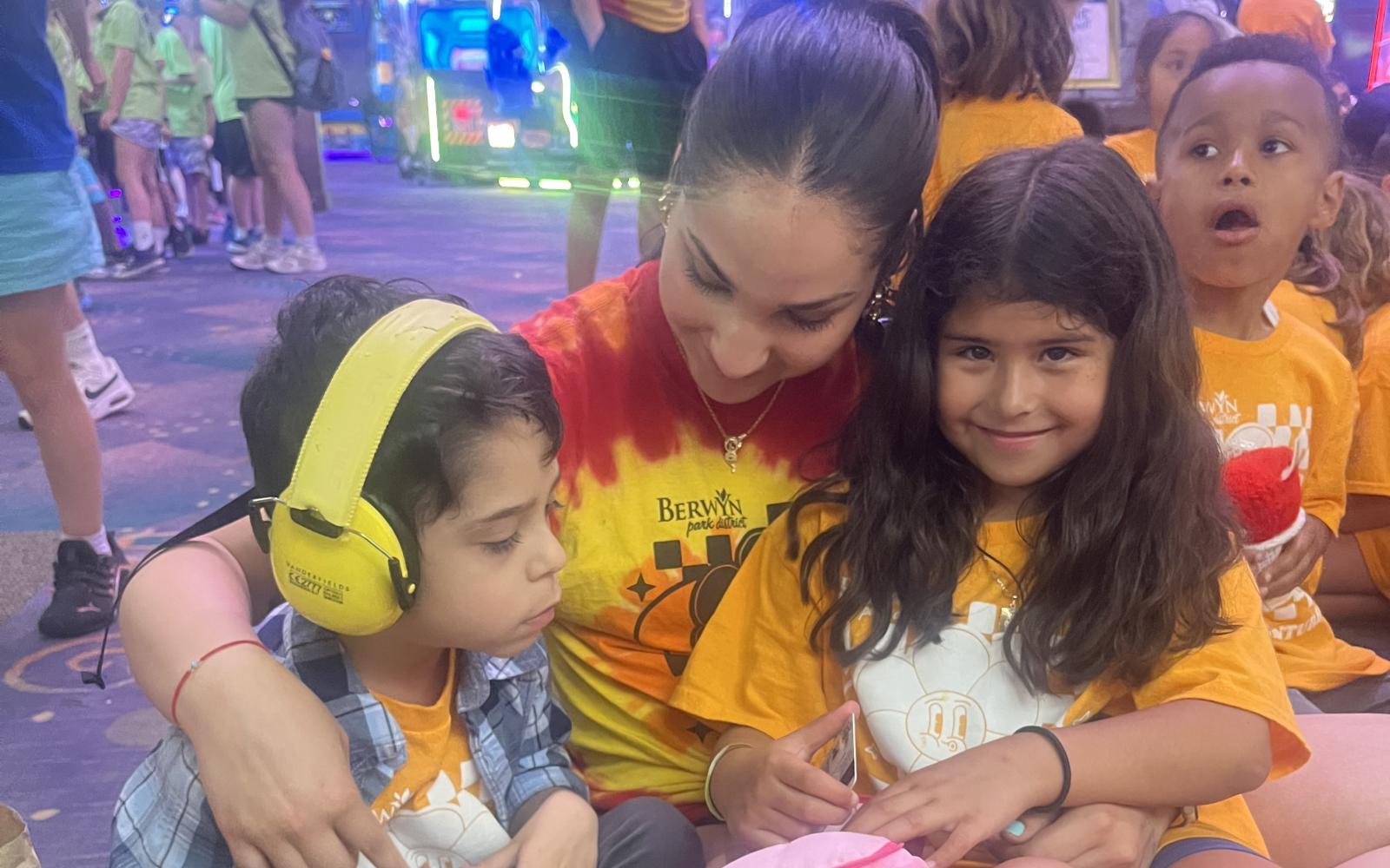 a camp counselor sitting with two campers at a field trip
