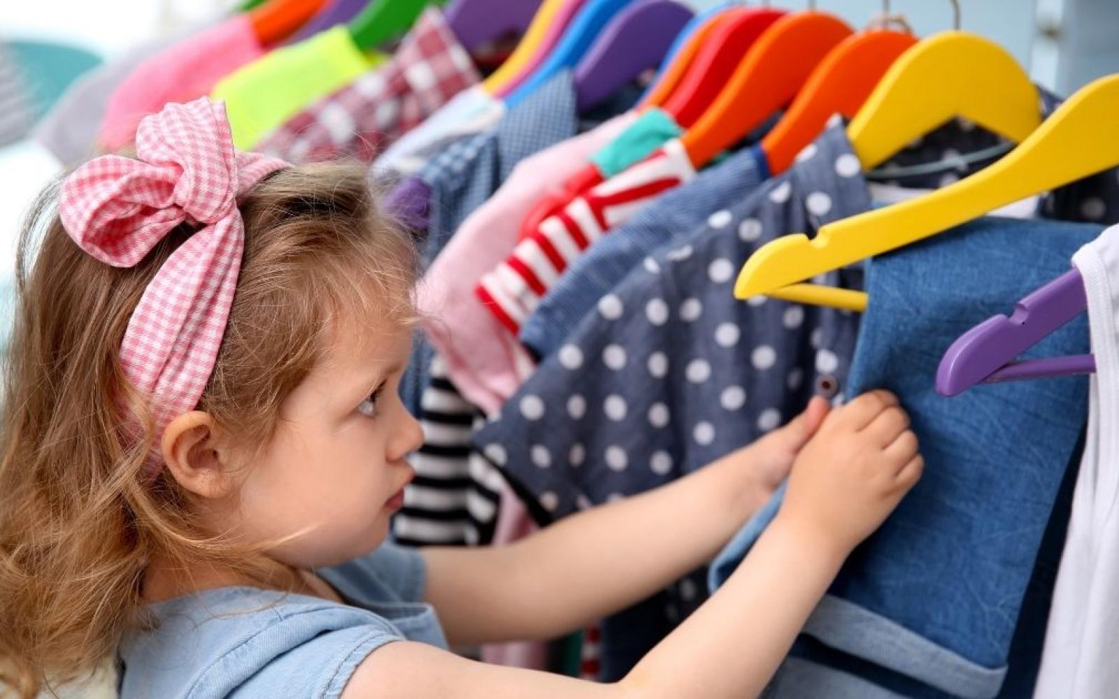 photo of a young girl going through hanging clothes for childrens clothing exchange